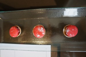 a row of red cookies on a glass table