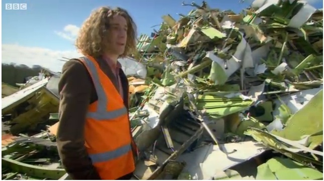 a man in an orange vest standing next to a pile of debris