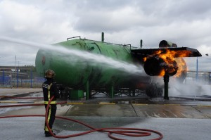a firefighter spraying water on a green tank
