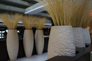 several large white vases with grass in them