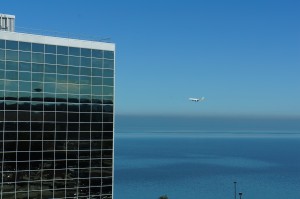a large building with windows and a plane flying over the water