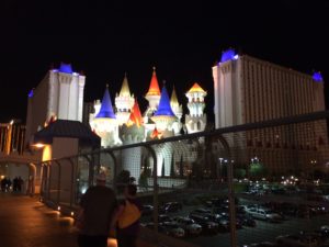 a group of people standing by a fence with a castle in the background with Excalibur Hotel and Casino in the background