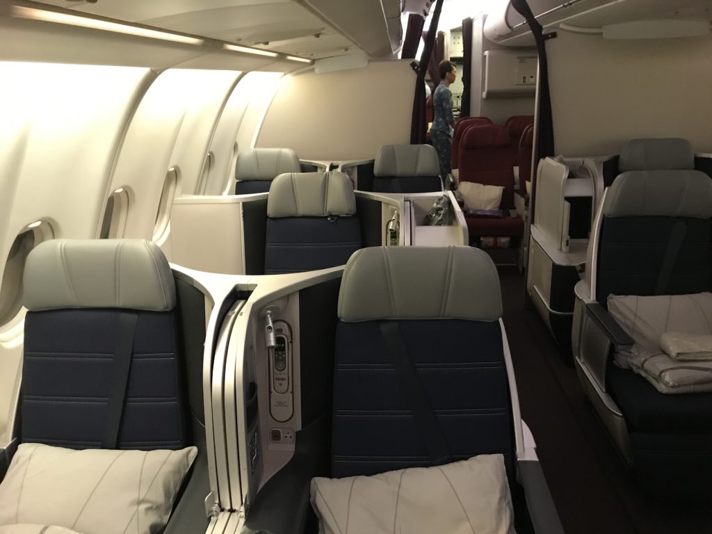 the inside of an airplane with seats and a person standing in the background