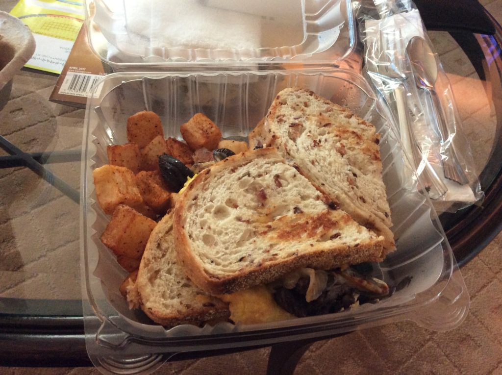 a sandwich and potatoes in a plastic container